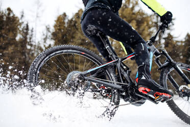 Ein Mittelteil eines Mountainbikers, der im Winter draußen im Schnee fährt. - HPIF21870