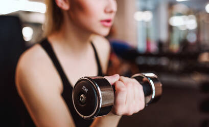 Ein junges Mädchen oder eine Frau mit Hanteln, die in einem Fitnessstudio trainieren. - HPIF21874