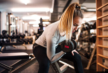 Ein junges Mädchen oder eine junge Frau mit Hanteln, die in einem Fitnessstudio trainieren. - HPIF21878