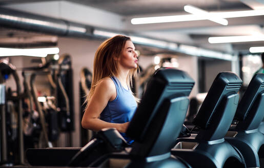 Ein Porträt eines schönen jungen Mädchens oder einer Frau beim Cardio-Training in einem Fitnessstudio. - HPIF21879