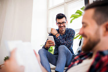 A group of young cheerful friends relaxing indoors, house sharing concept. - HPIF21912