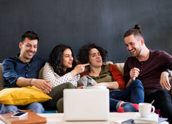 Eine Gruppe junger, fröhlicher Freunde mit Smartphone sitzt drinnen auf dem Sofa und sieht sich einen Film an. Hausgemeinschaftskonzept. - HPIF21952