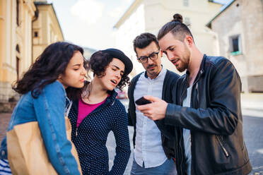 Eine Gruppe junger Freunde steht in der Stadt im Freien und benutzt ihr Smartphone. - HPIF21982