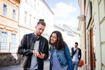 Junge glückliche Freunde mit einem Smartphone, die draußen in der Stadt stehen und sich unterhalten. - HPIF21986