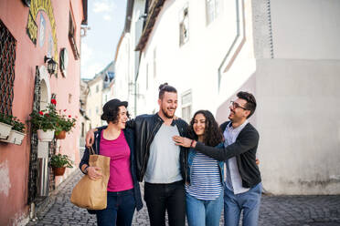 Eine Gruppe junger Freunde, die draußen in der Stadt spazieren gehen, sich unterhalten und Spaß haben. - HPIF22002