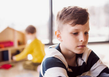 A portrait of small boy sitting on the floor at home. Copy space. - HPIF22043