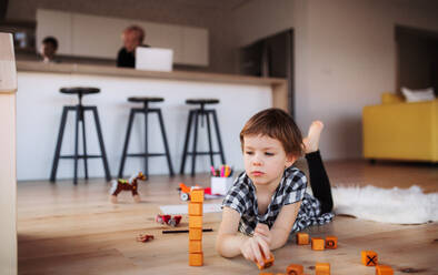 Ein kleines Mädchen, das zu Hause auf dem Boden mit Bauklötzen spielt. - HPIF22071