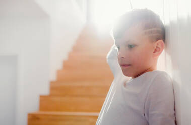 Ein kleiner Junge, der drinnen an der Holztreppe steht. Raum kopieren. - HPIF22085