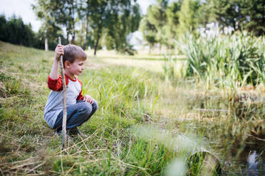 Side view portrait of school child on field trip in nature, looking at pond. - HPIF22125