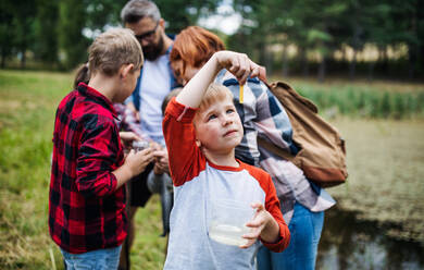 Eine Gruppe von kleinen Schulkindern mit einem Lehrer auf einem Ausflug in die Natur, um Wissenschaft zu lernen. - HPIF22129