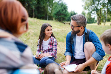 A group of small school children with teacher on field trip in nature, learning science. - HPIF22133