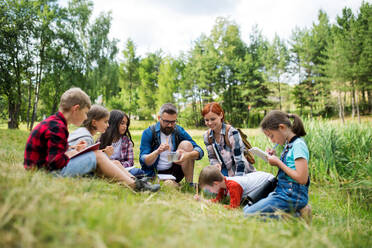 Eine Gruppe von kleinen Schulkindern mit einem Lehrer auf einem Ausflug in die Natur, um Wissenschaft zu lernen. - HPIF22134