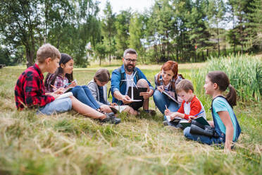 A group of school children with teacher and windmill model on field trip in nature. - HPIF22136