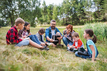Eine Gruppe von Schulkindern mit Lehrer und Windmühlenmodell auf einem Ausflug in die Natur. - HPIF22136