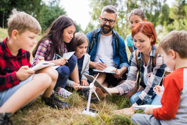 Eine Gruppe von Schulkindern mit Lehrer und Windmühlenmodell auf einem Ausflug in die Natur. - HPIF22139