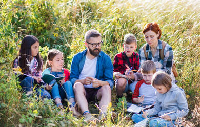 A group of small school children with teacher on field trip in nature, learning. - HPIF22149