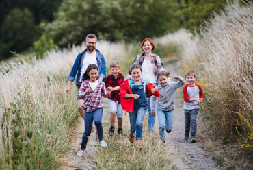 Eine Gruppe von kleinen Schulkindern mit Lehrer auf Exkursion in der Natur, beim Laufen. - HPIF22154