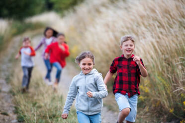 Portrait of group of school children running on field trip in nature. - HPIF22155