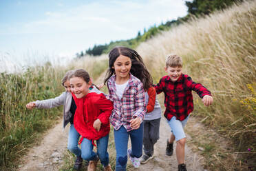 Portrait of group of school children running on field trip in nature. - HPIF22159