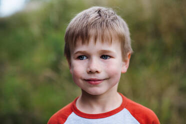 A portrait of blond school boy standing in nature, looking at camera. - HPIF22168