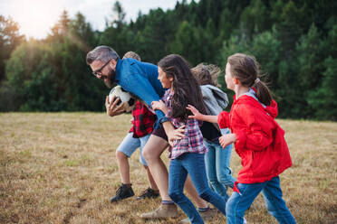 Eine Gruppe von kleinen Schulkindern mit Lehrer auf Exkursion in der Natur, beim Laufen. - HPIF22172