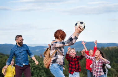 Eine Gruppe kleiner Schulkinder mit Lehrer auf einem Ausflug in die Natur, die mit einem Ball spielen. - HPIF22176