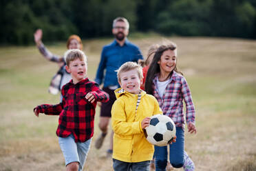 Eine Gruppe kleiner Schulkinder mit Lehrer auf einem Ausflug in die Natur, die mit einem Ball spielen. - HPIF22179