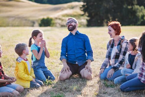 Eine Gruppe von kleinen Schulkindern mit Lehrer auf Exkursion in der Natur, lachend. - HPIF22190