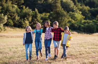 A group of school children walking on field trip in nature, arm in arm. - HPIF22193