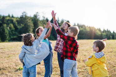 Porträt einer Gruppe von Schulkindern, die auf einem Ausflug in die Natur stehen und sich gegenseitig die Hand geben. - HPIF22194