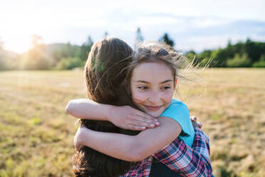 Zwei fröhliche Schulkinder auf einem Ausflug in die Natur, die sich umarmen. - HPIF22195