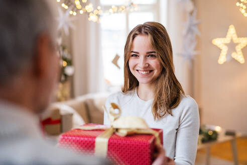 Porträt einer jungen Frau, die ihrem nicht identifizierbaren Großvater zu Weihnachten ein Geschenk überreicht. - HPIF22242