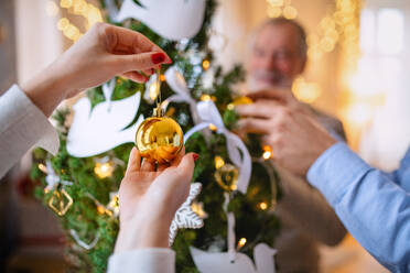 Mittelteil einer nicht wiederzuerkennenden Verwandtschaft zu Hause beim Schmücken des Weihnachtsbaums. - HPIF22251