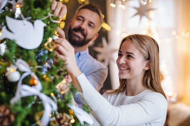 Porträt eines glücklichen Paares zu Hause beim Schmücken des Weihnachtsbaums. - HPIF22254