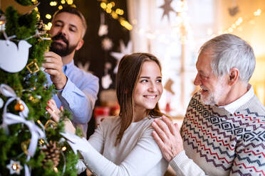 Happy men and woman family relatives indoors at home at Christmas, decorating tree. - HPIF22255