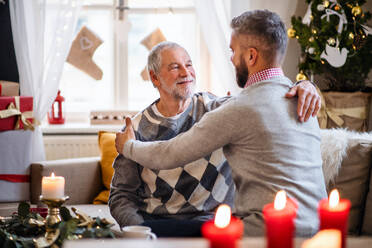 Glücklicher reifer Mann und älterer Vater zu Hause an Weihnachten, die sich umarmen. - HPIF22262