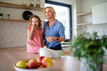 Ein glückliches süßes kleines Mädchen mit Mutter drinnen in der Küche zu Hause. - HPIF22350