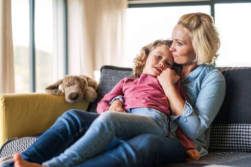 Ein niedliches kleines Mädchen mit seiner Mutter auf dem Sofa zu Hause und ruht sich aus. - HPIF22364