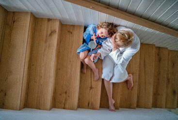 Draufsicht auf ein kleines Mädchen mit seiner Mutter zu Hause auf der Treppe sitzend am Morgen. - HPIF22394