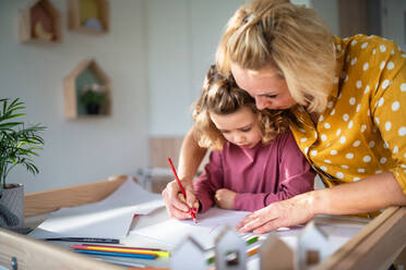 A cute small girl with mother in bedroom indoors at home, drawing pictures. - HPIF22399