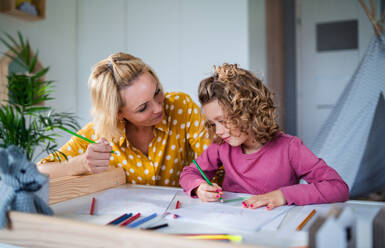 A cute small girl with mother in bedroom indoors at home, drawing pictures. - HPIF22403