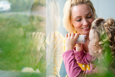 A cute small girl with mother indoors at home, playing with toy binoculars. Copy space. - HPIF22413