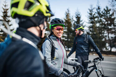 Eine Gruppe junger Mountainbiker steht im Winter auf der Straße und unterhält sich. - HPIF22419