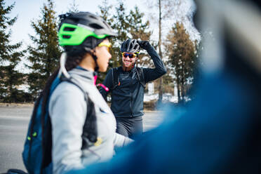 Eine Gruppe junger Mountainbiker steht im Winter auf der Straße und unterhält sich. - HPIF22420