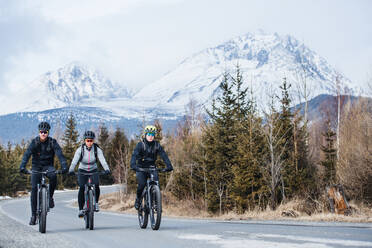 A group of young mountain bikers riding on road outdoors in winter. - HPIF22424