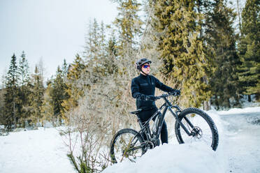 Ein männlicher Mountainbiker fährt im Schnee draußen in der winterlichen Natur. - HPIF22455