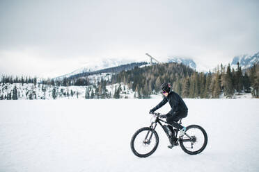Eine Seitenansicht von Mountainbiker Reiten im Schnee im Freien im Winter Natur. - HPIF22458
