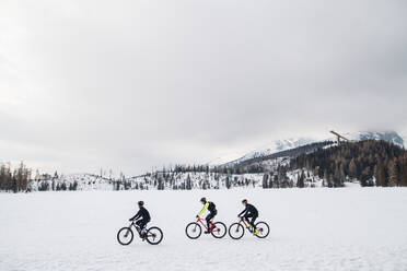 A side view of group of mountain bikers riding outdoors in winter. - HPIF22459