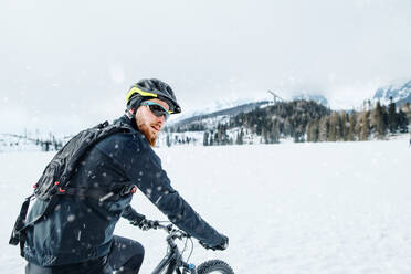 Eine Seitenansicht von Mountainbiker Reiten im Schnee im Freien im Winter Natur. - HPIF22460