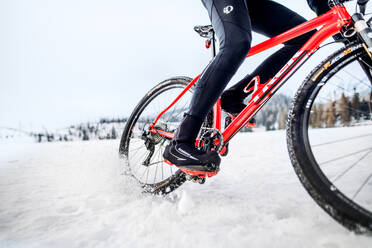 Ein Mittelteil eines Mountainbikers, der im Winter draußen im Schnee fährt. - HPIF22462